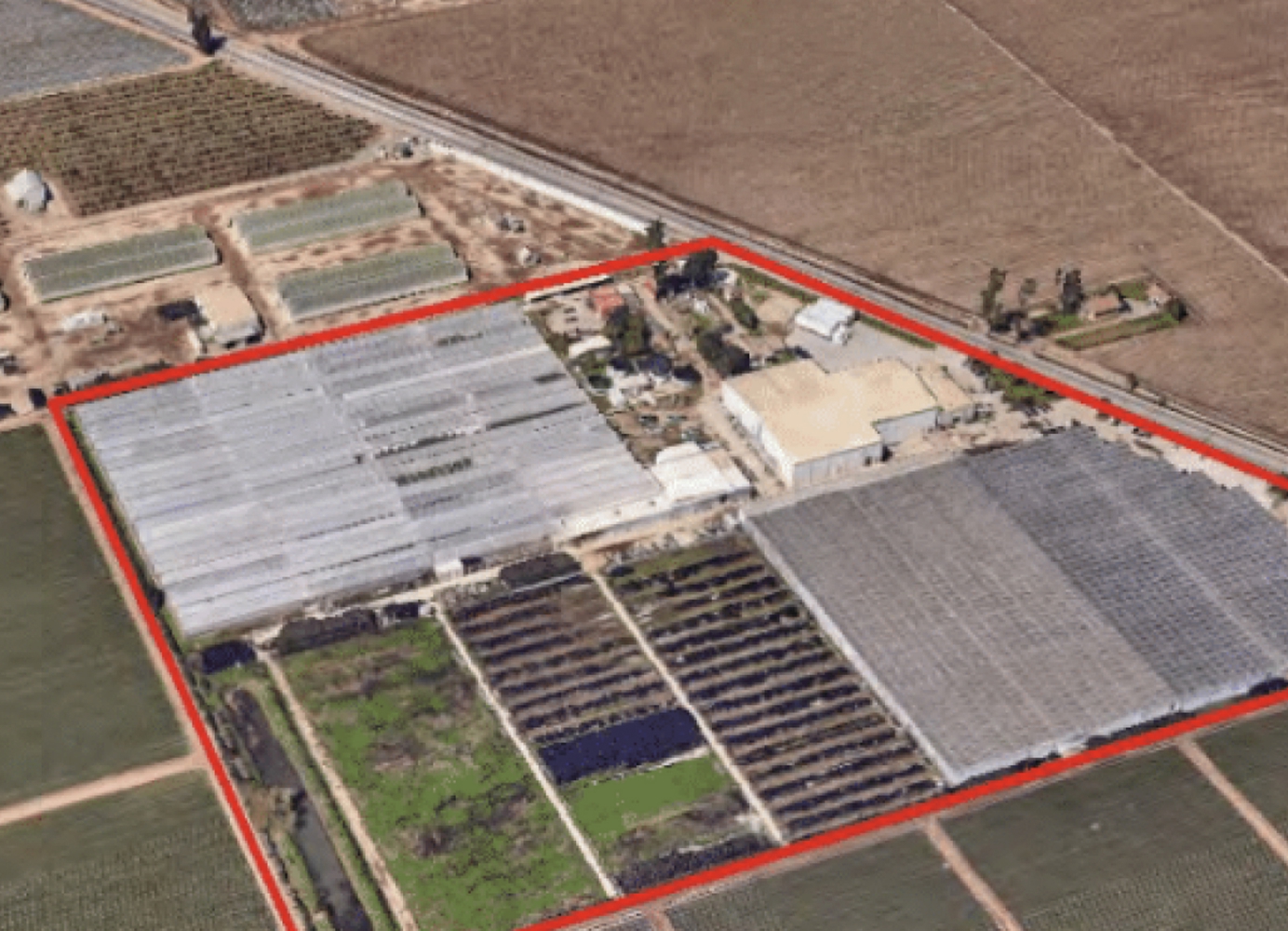 Aerial view of a greenhouse and agricultural property outlined in red, surrounded by farmland.