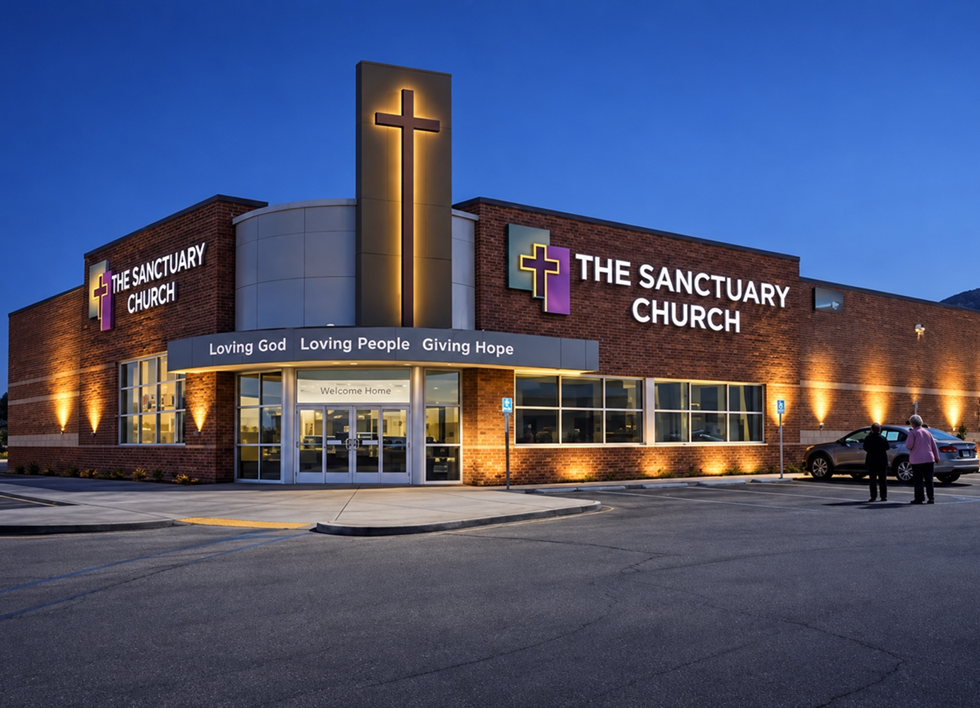 Exterior of The Sanctuary Church at dusk, featuring illuminated signage and a large cross above the main entrance.