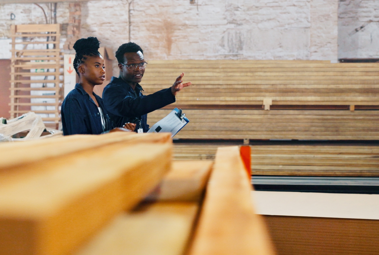 Two people inspecting materials inside a lumber warehouse.