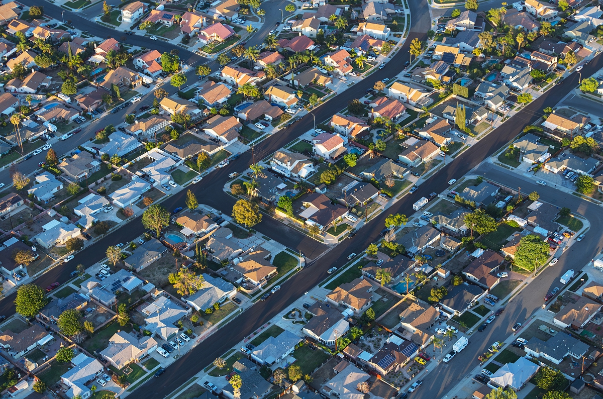 Aerial view of a suburban residential neighborhood with single-family homes and tree-lined streets.