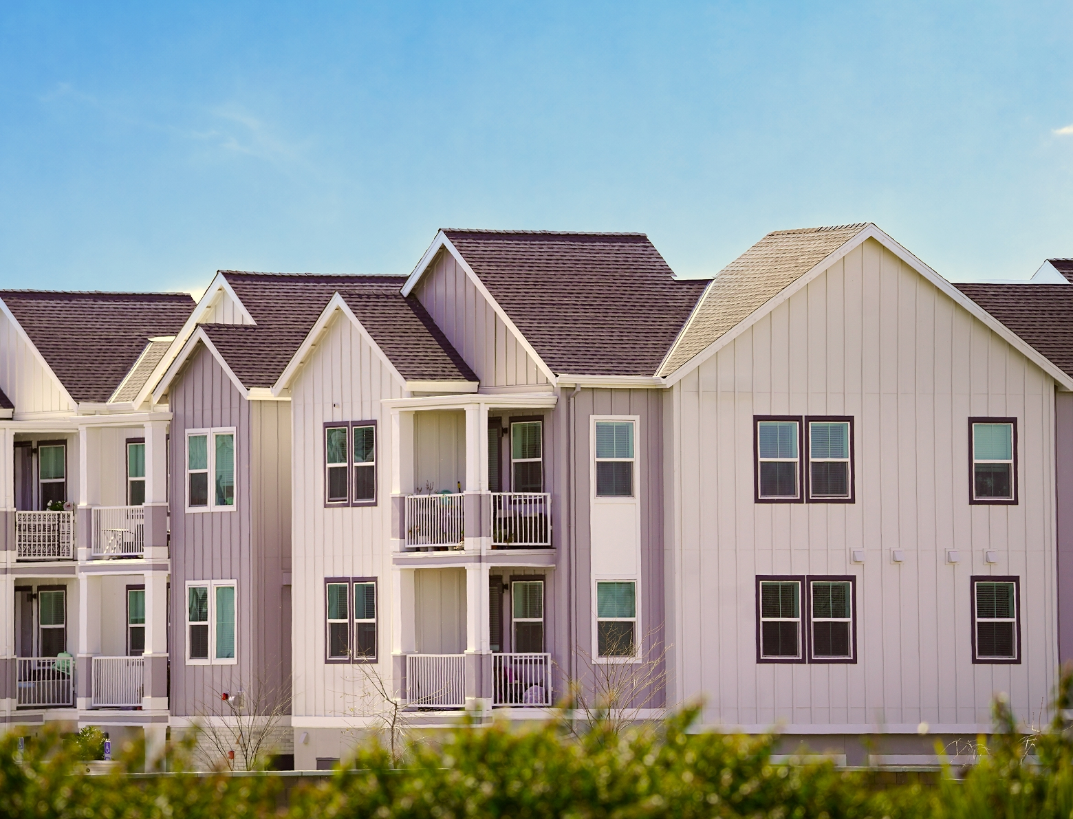 Exterior of a multi-unit residential building with balconies and gabled roofs.