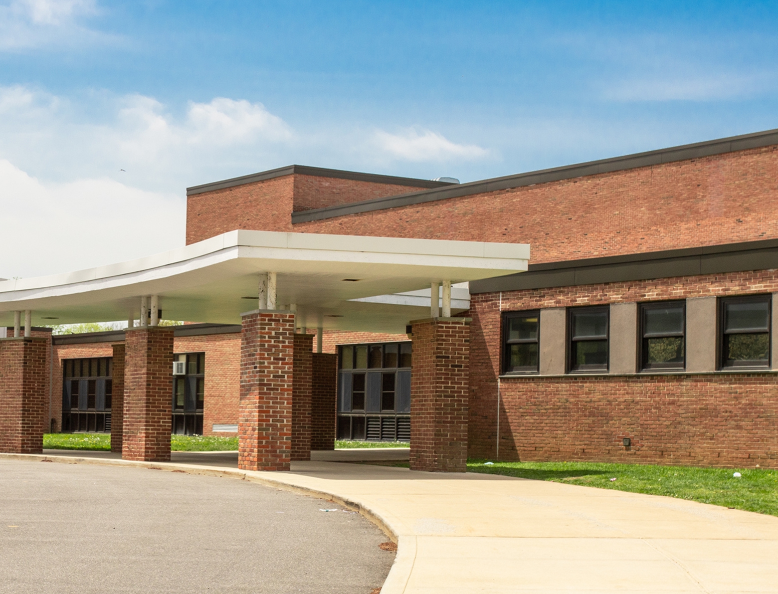 Exterior of a brick institutional building with a covered entrance and walkway.